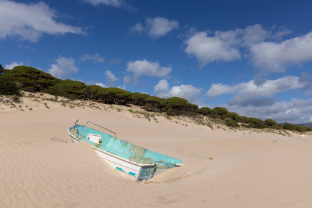 Beached old abandoned boat on the seashore stranded and full of sand in Punta Paloma on a bright sunny day with blue sky.の写真素材