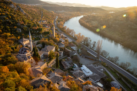 A breathtaking aerial view of a winding river embraced by vibrant autumn hues, showcasing traditional architecture nestled harmoniously in nature.の写真素材