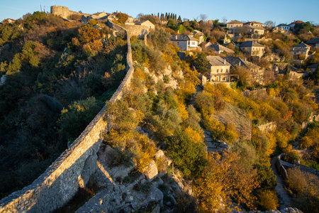 An elevated shot capturing the essence of a hillside showcasing a beautiful blend of autumn foliage and traditional architecture bathed in golden sunlight.の写真素材