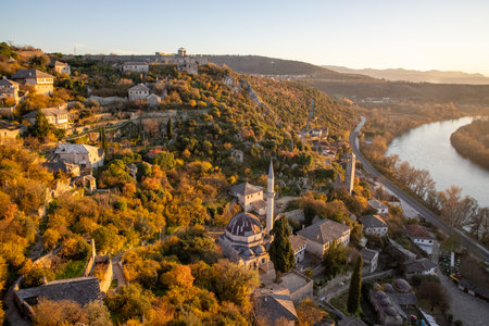 This stunning panoramic view captures the essence of nature's beauty, showcasing a quaint village enveloped by vibrant autumn colors and rolling hills in a serene setting.の写真素材