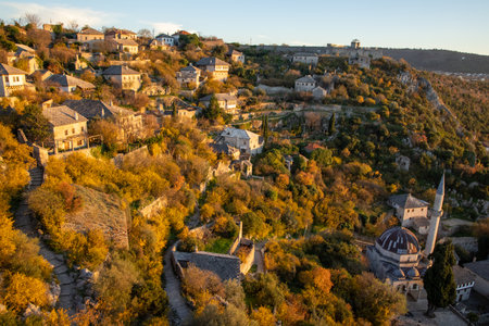 This image showcases a picturesque hillside village during the fall, highlighting the rich autumn colors of the landscape and the charming architecture of the homes.の写真素材