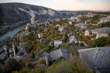 A breathtaking panoramic view of a charming old village located on a hillside, surrounded by lush greenery and the flowing river nearby, showcasing tranquility and beauty.の写真素材