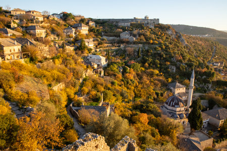 A stunning view through ancient ruins, capturing a tranquil village enveloped in warm autumn hues, encapsulating the beauty of nature and the passage of time.の写真素材