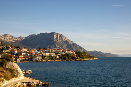 A beautiful coastal village nestled against majestic mountains, showcasing charming architecture and vibrant landscapes under a clear blue sky that invites exploration.の写真素材