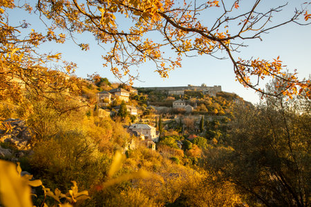 A picturesque hillside village set against a backdrop of colorful autumn foliage, inviting viewers to explore its charming architecture and serene landscape.の写真素材