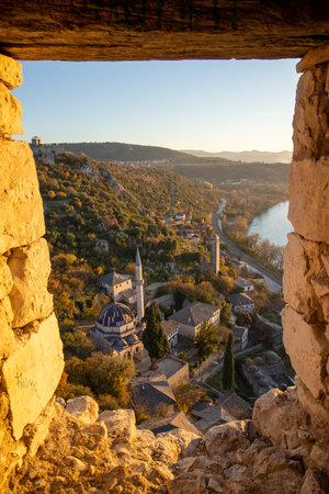 A unique framed perspective of a captivating landscape showcasing ancient architecture and a serene river lined with autumn foliage, evokes tranquility.の写真素材