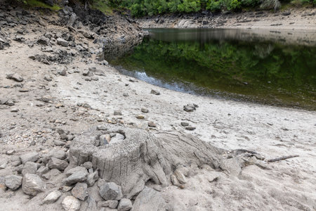 The image presents a high-angle, close-up view of a stark, arid landscape.  The foreground is dominated by light grey, cracked earth scattered with small to medium-sized rocks and pebbles.の写真素材
