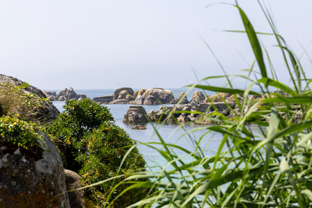 A rocky shoreline with a body of water in the background. The water is blue and the shoreline is...