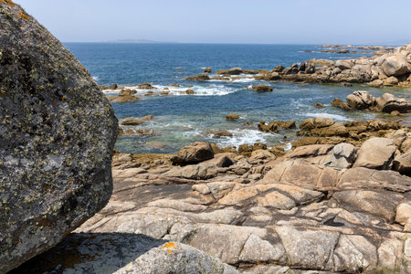 A rocky shoreline with the ocean. The sky is clear and the ocean is calmの写真素材