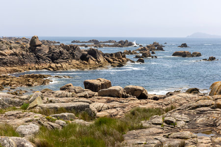 A rocky shoreline with a large rock in the foreground. The rocks are scattered along the shoreline, and the water is calm. The scene has a peaceful and serene mood, with the rocksの写真素材