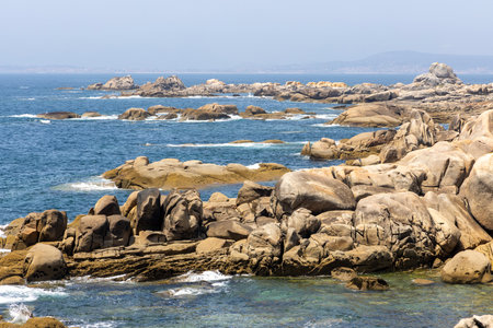 A rocky shoreline with a calm ocean in the background. The rocks are scattered across the beach, creating a rugged and natural landscape. Concept of tranquility and serenityの写真素材