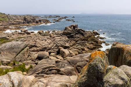 A rocky shoreline with a calm ocean in the background. The rocks are scattered across the beach, creating a rugged and natural landscape. Concept of tranquility and serenityの写真素材