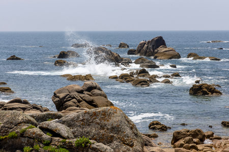 The ocean is calm and the rocks are scattered along the shore. The rocks are of various sizes and shapes, and they are scattered along the shoreline. The water is a deep blue colorの写真素材