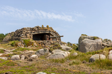 A large stone building with a gun on top of it. The building is surrounded by rocks and has a stone wall. Scene is one of strength and protectionの写真素材