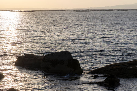 The ocean is calm and the sun is setting. The water is a deep blue color and the sky is a light blue colorの写真素材