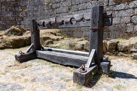 A wooden structure with a metal chain hanging from it. The chain is attached to a wooden post. The...