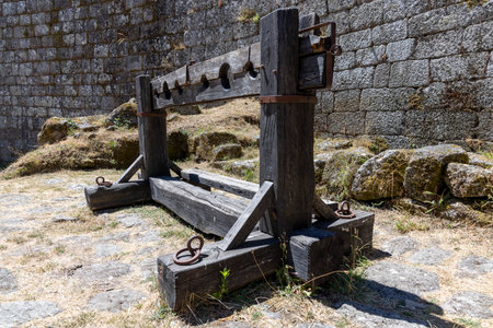 A wooden structure with a metal chain hanging from it. The chain is attached to a wooden post. The...