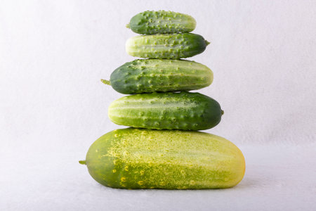 A stack of cucumbers on a white background. The cucumbers are green and yellow. Concept of freshness and healthinessの写真素材