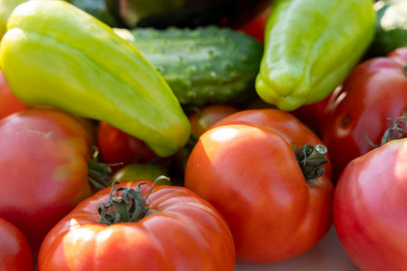 A variety of vegetables, including tomatoes and cucumbers, are displayed together. The tomatoes are red and the cucumbers are green. The arrangement of the vegetables creates a visually appealingの写真素材