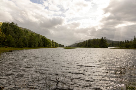 A calm lake with a cloudy sky in the background. The water is still and the sky is overcast