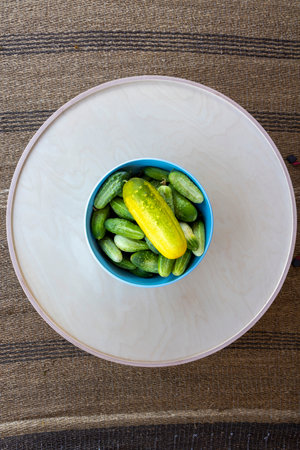 A bowl of pickles sits on a table. The pickles are green and yellow, and there are several of them in the bowlの写真素材