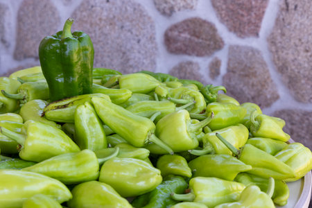 A bunch of green peppers are piled on top of each other. The peppers are all different sizes and are arranged in a way that they are all visible. Concept of abundance and freshnessの写真素材