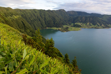 A beautiful view of a lake with mountains in the background. The lake at Sete Cidades, Azores is surrounded by lush green trees and the mountains are covered in trees as well.の写真素材