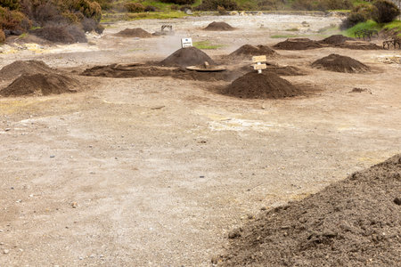 A bunch of caldeira holes for geothermal cooking with a pile of rocks in the middle. The rocks are scattered around the field and some are piled up at Furnas, Azoresの写真素材