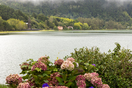 A beautiful view of a lake with a church in the background. The water is calm and the sky is cloudy at Nossa Senhora das Vitorias, Furnasの写真素材