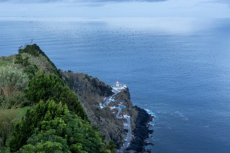 A beautiful view of the ocean with a lighthouse in the distance. The water is calm and the sky is clearの写真素材