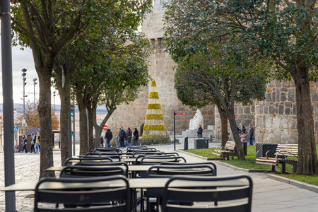 Avila, Spain, December 10, 2025: A city street with a large Christmas tree in the middle. There are...