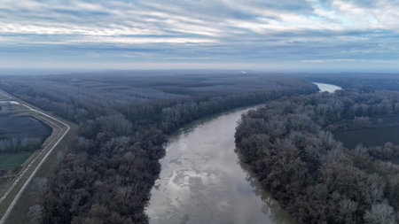 Tisza river winding through bare trees and fields under overcast sky in winter