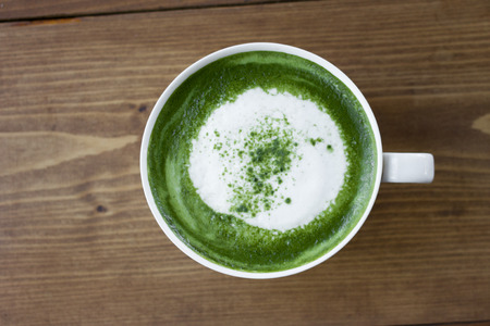 Matcha green tea latte beverage in glass on table.
