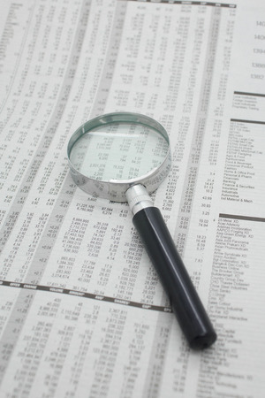 Magnifier rest on stock price detail financial newspaper.の写真素材