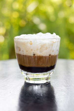 Hot espresso coffee with white cream on table.