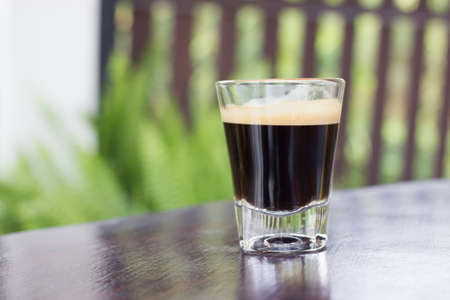 Cup of black coffee with foam on a table.の写真素材
