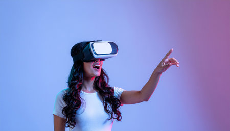 Young woman using virtual reality headset and gesturing while standing against purple backgroundの素材