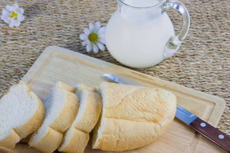fresh cut long loaf and milk in a jugの写真素材