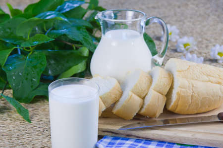 fresh cut long loaf and milk in a jugの写真素材