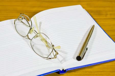 a notebook, a pair of glasses and a penの写真素材