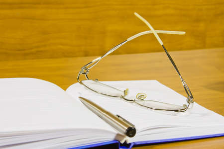 a notebook, a pair of glasses and a penの写真素材