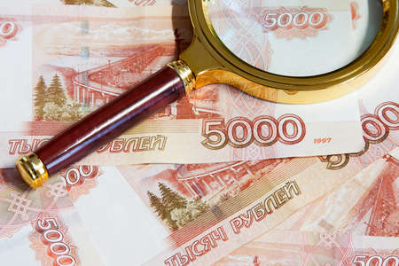 The magnifier in the gilt frame lays on the Russian money