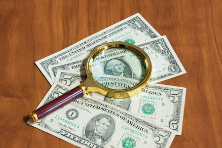 The magnifier in the gilt frame lays on dollars