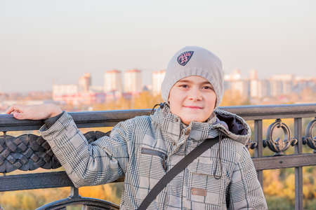 Tyumen, Russia - October 01.2016: Cheerful boy on a background of modern buildings around a decorative fenceの写真素材