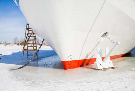 Fragment of a three-deck motor ship with an anchor in the ice in the backwaters of the riverの写真素材
