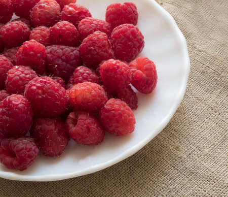 handful of fresh raspberries lying on a plateの写真素材
