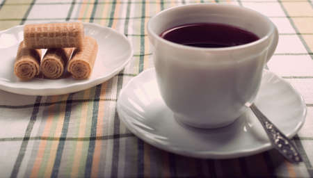 Vintage.Standing on the table white Cup with a tea of hibiscus in the foreground. The background is a plate of cookies.の写真素材
