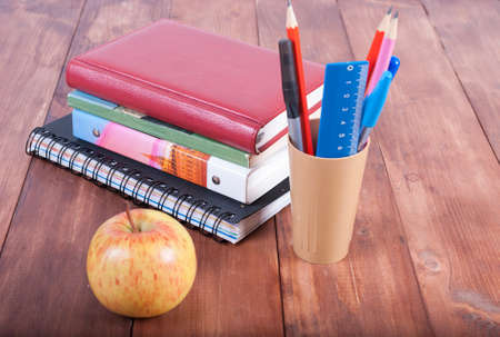 Stationery set and a stack of books on a wooden table