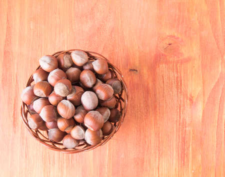 Hazelnuts in a basket on a wooden tableの写真素材