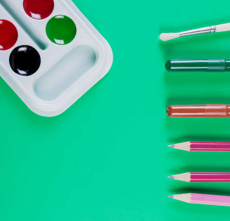 Watercolor paints and pencils on a green background. top viewの写真素材